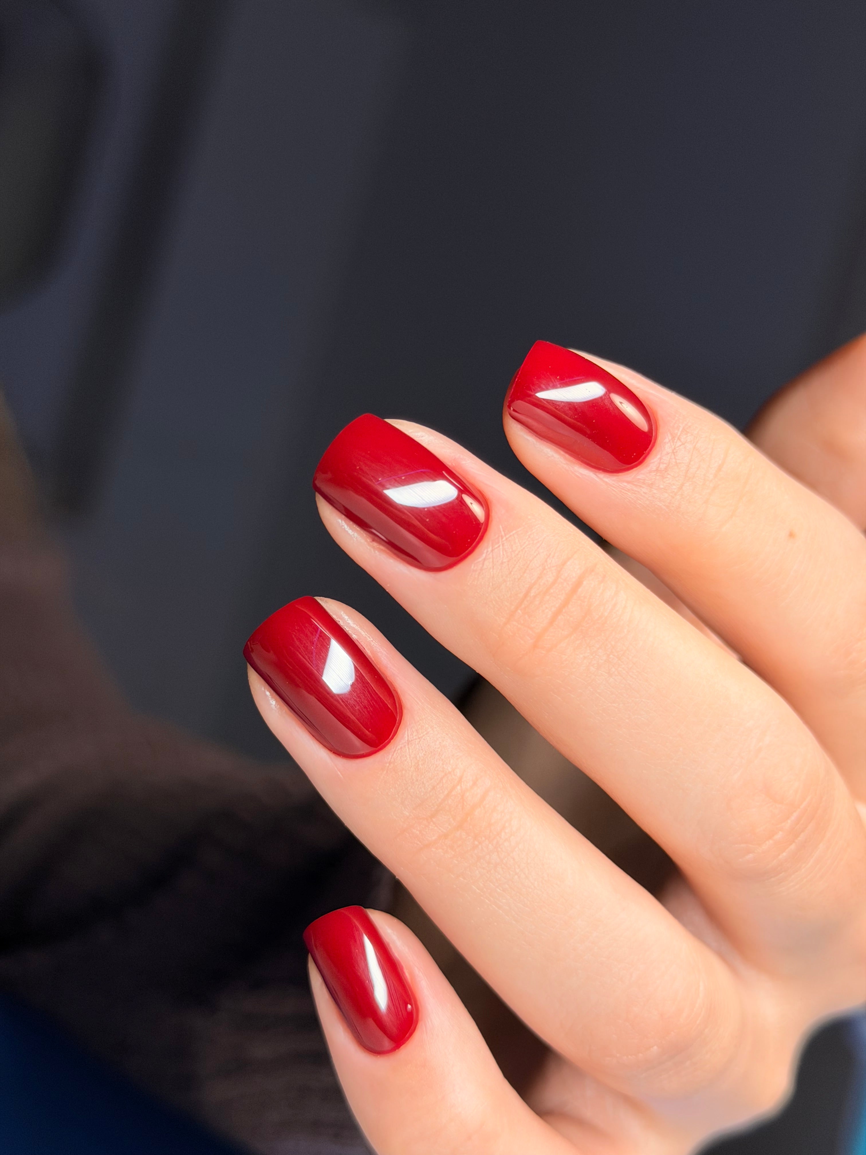 Close-up of a hand with red nail polish on a dark background
