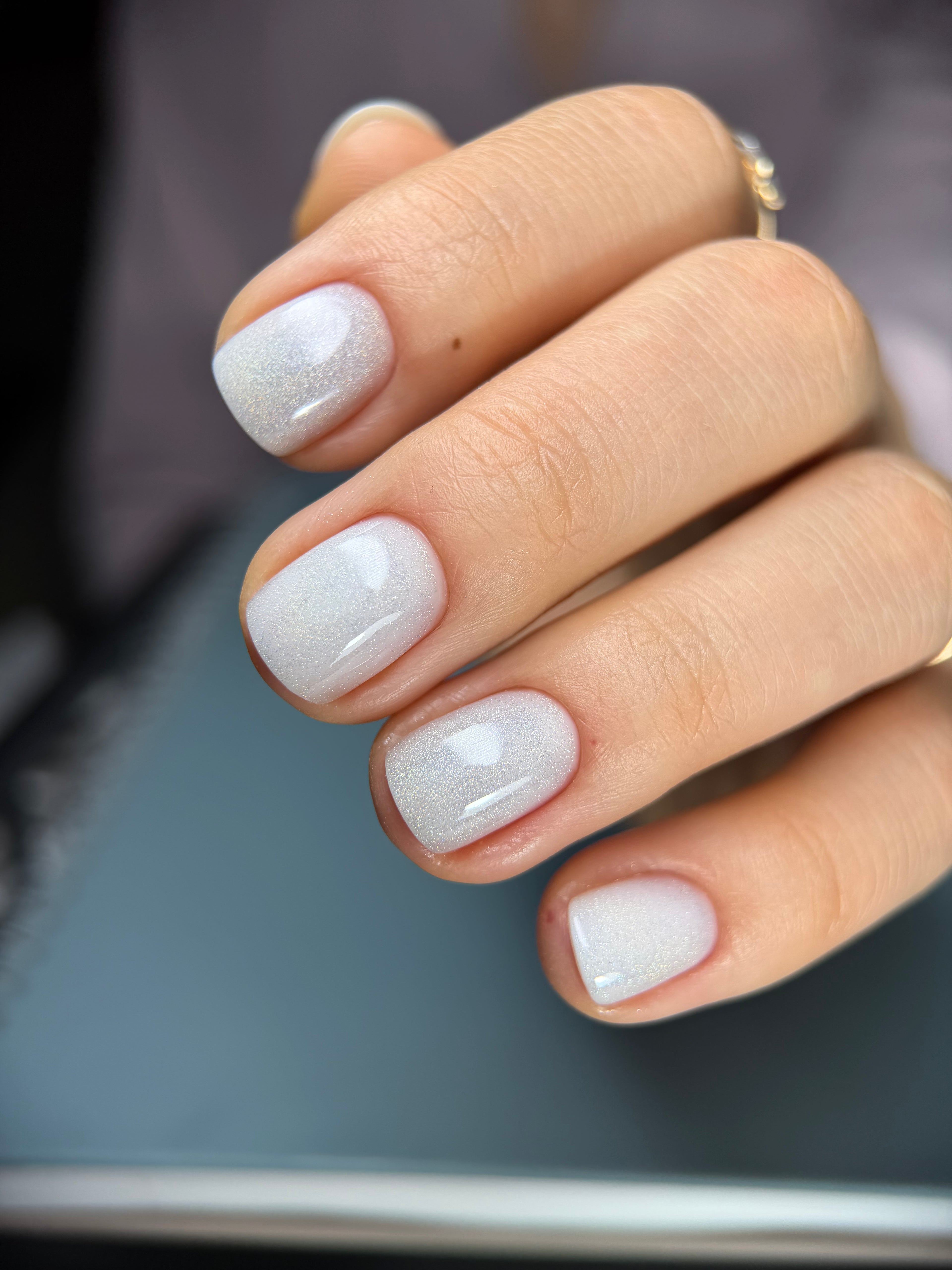 Close-up of a hand with white nail polish on a blurred background