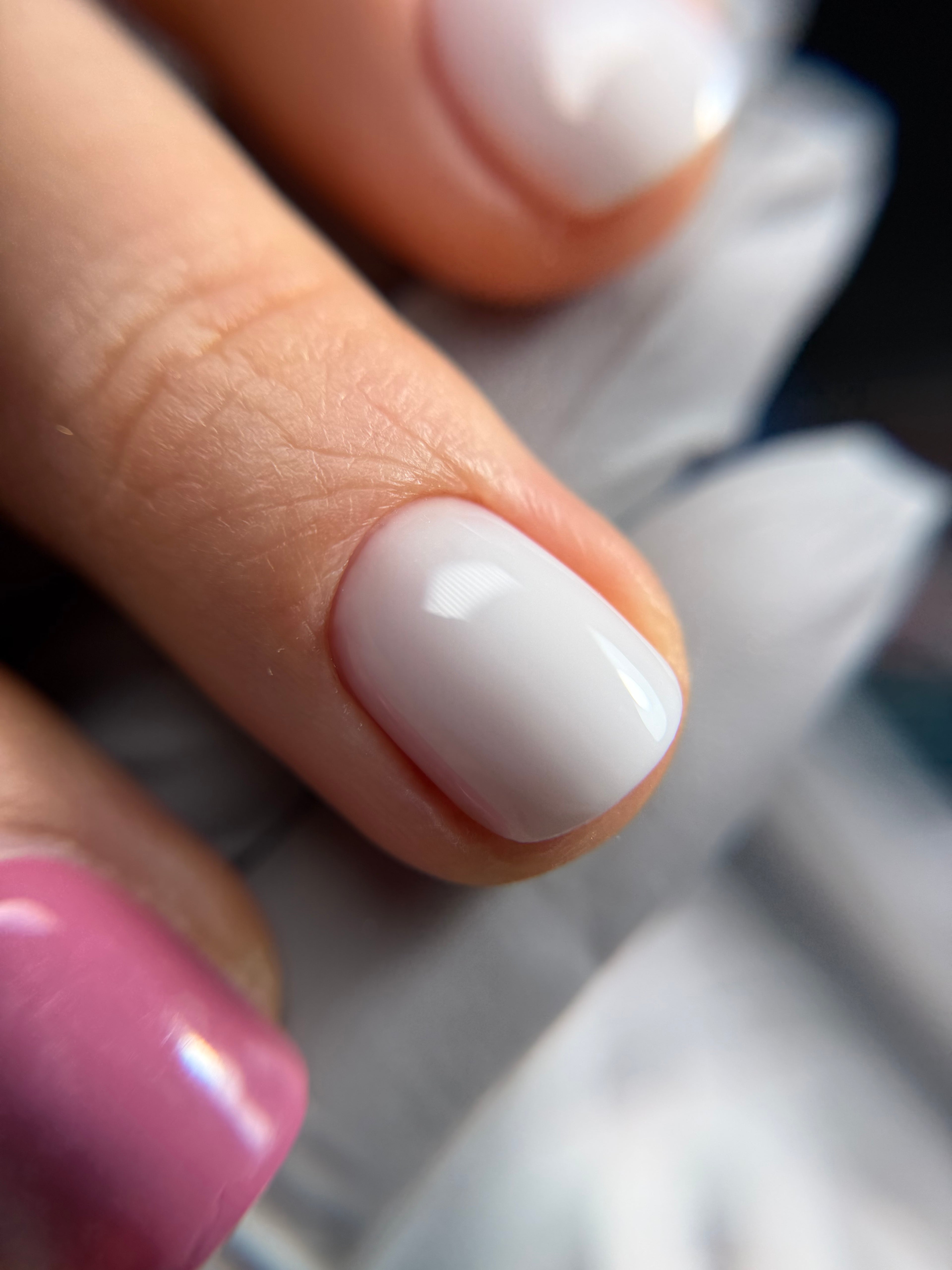Close-up of a hand with a white nail polish on a blurred background