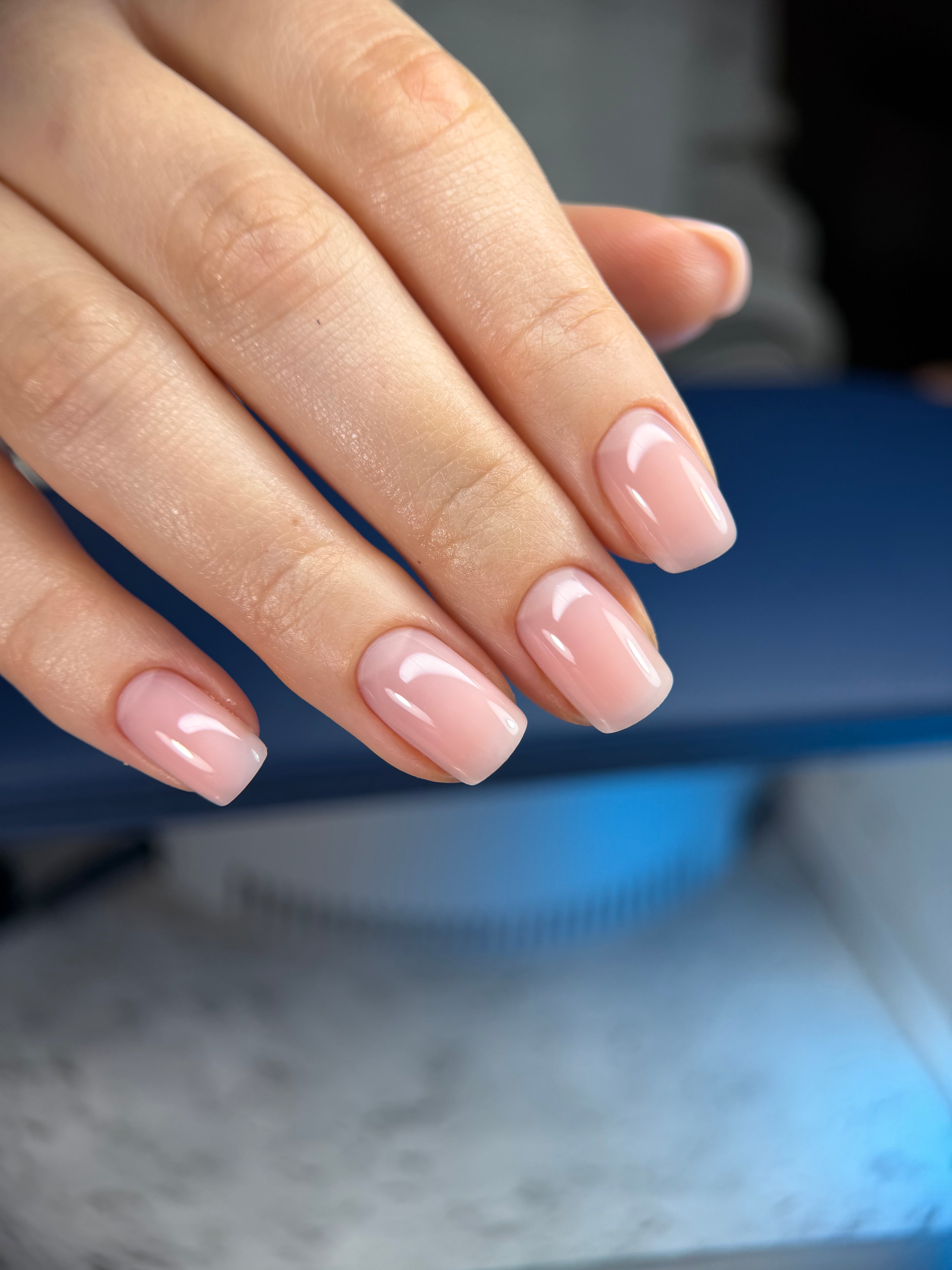 Close-up of a hand with pink nail polish against a blurred background