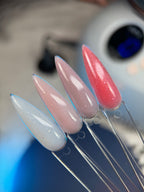 Set of long, pointed artificial nails in pink and white on a clear stand.