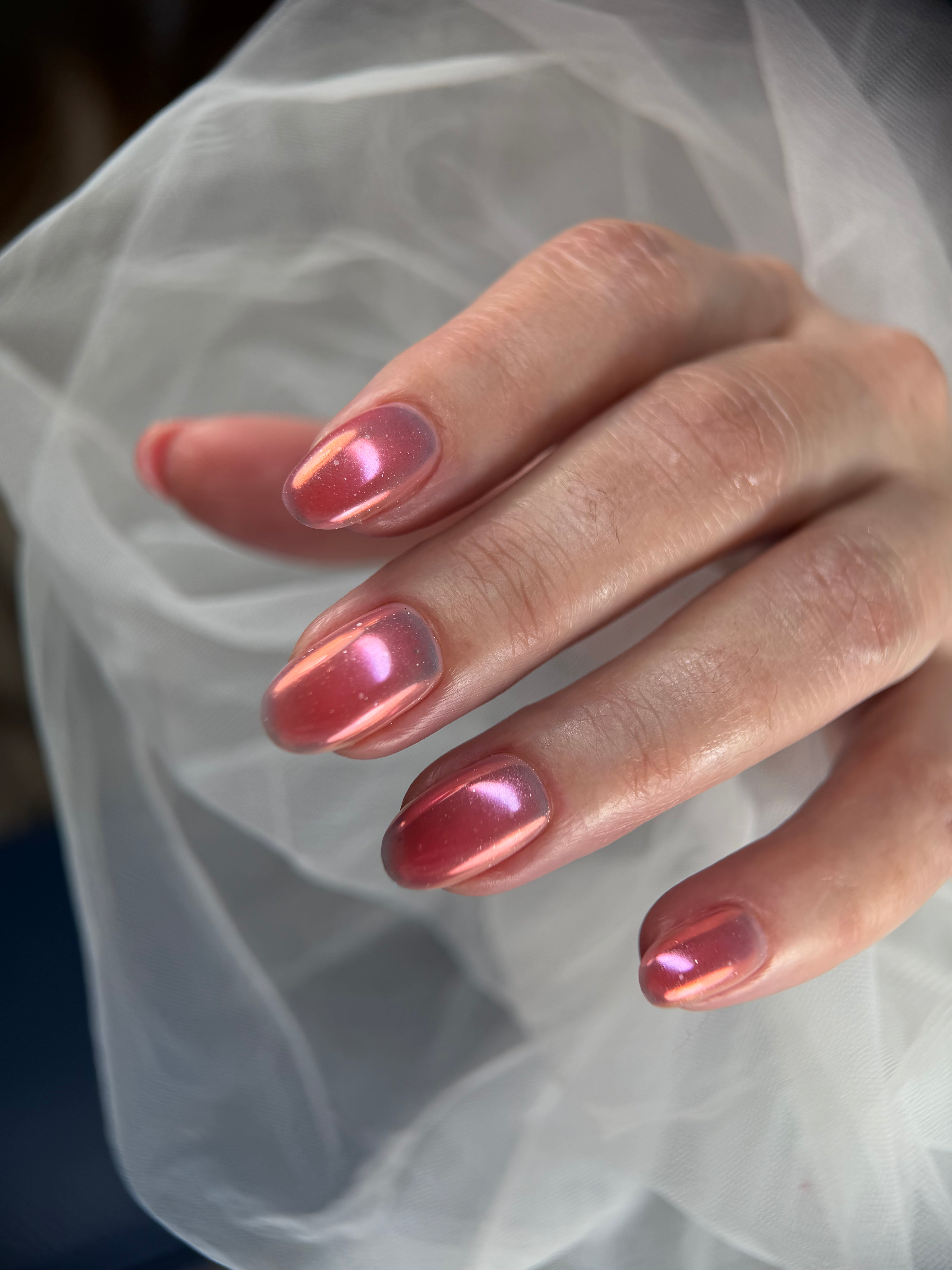 Close-up of a hand with pink nail polish against a light fabric background