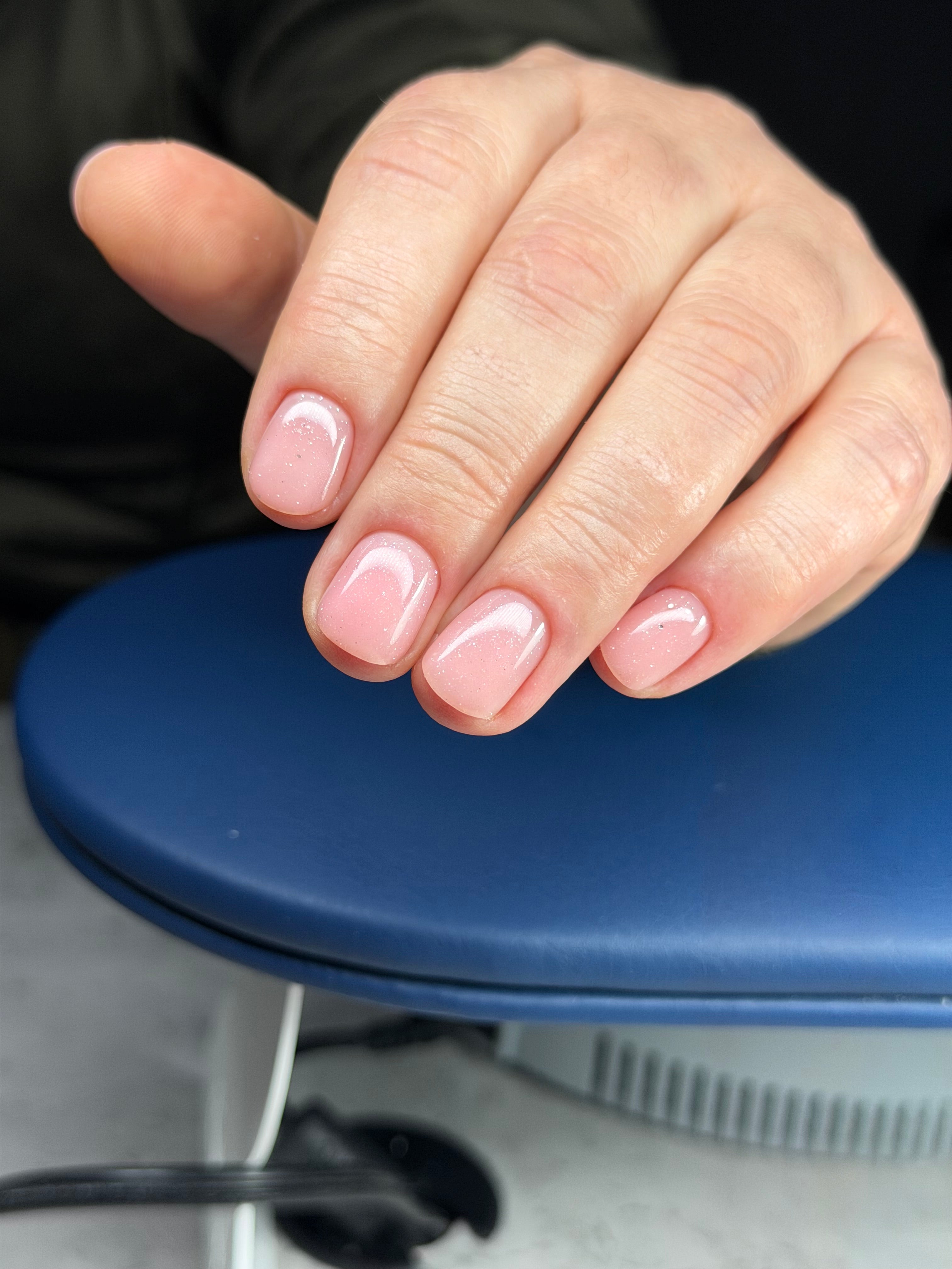 Hand with pink nail polish on a blue car door handle