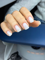 Close-up of a hand with white nail polish in an interior setting