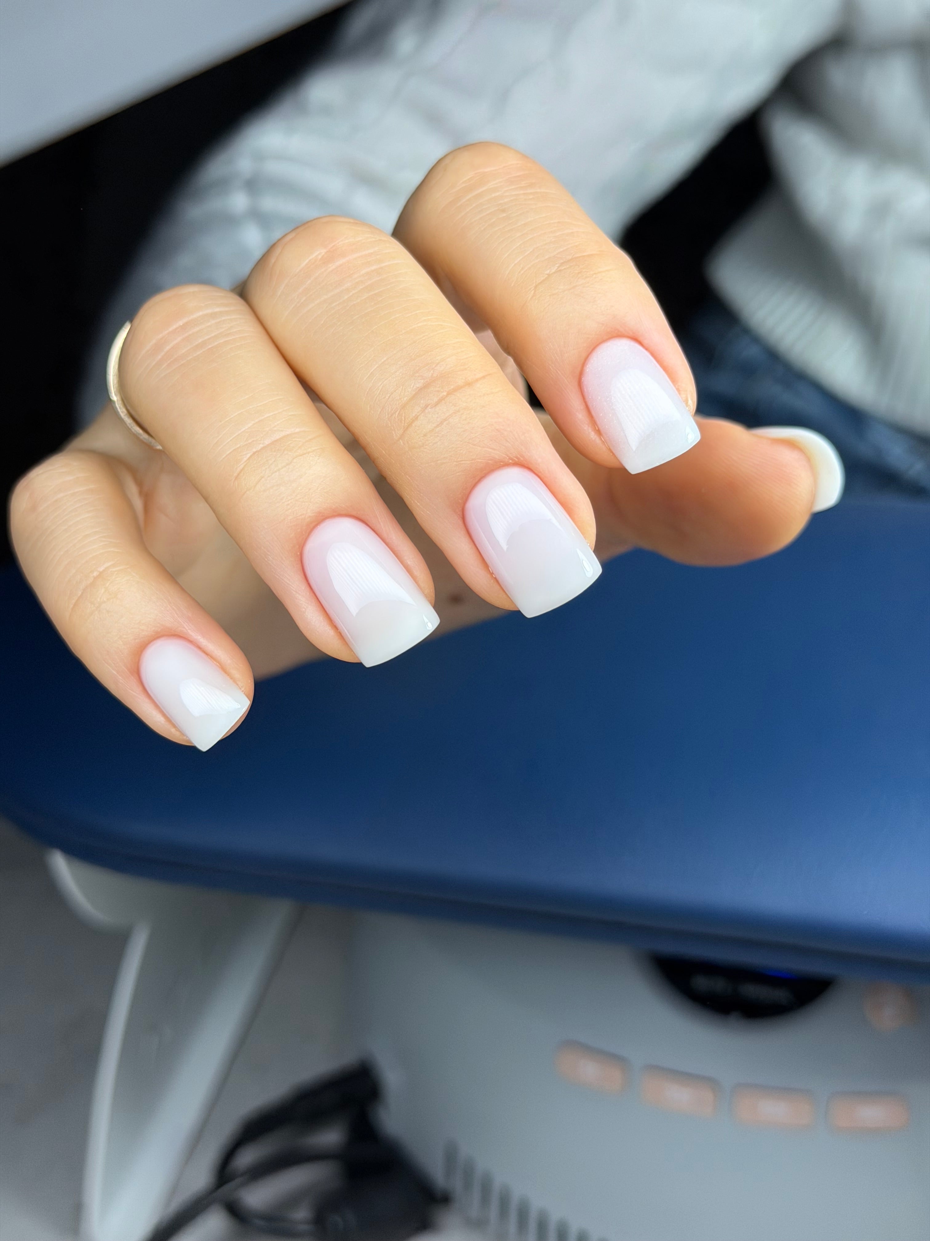 Close-up of a hand with white nail polish in an interior setting