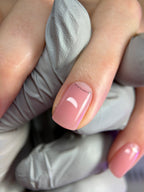 Close-up of a hand with pink nail polish and a small decorative element