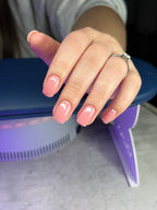 Hand with pink nail polish resting on a purple background device.