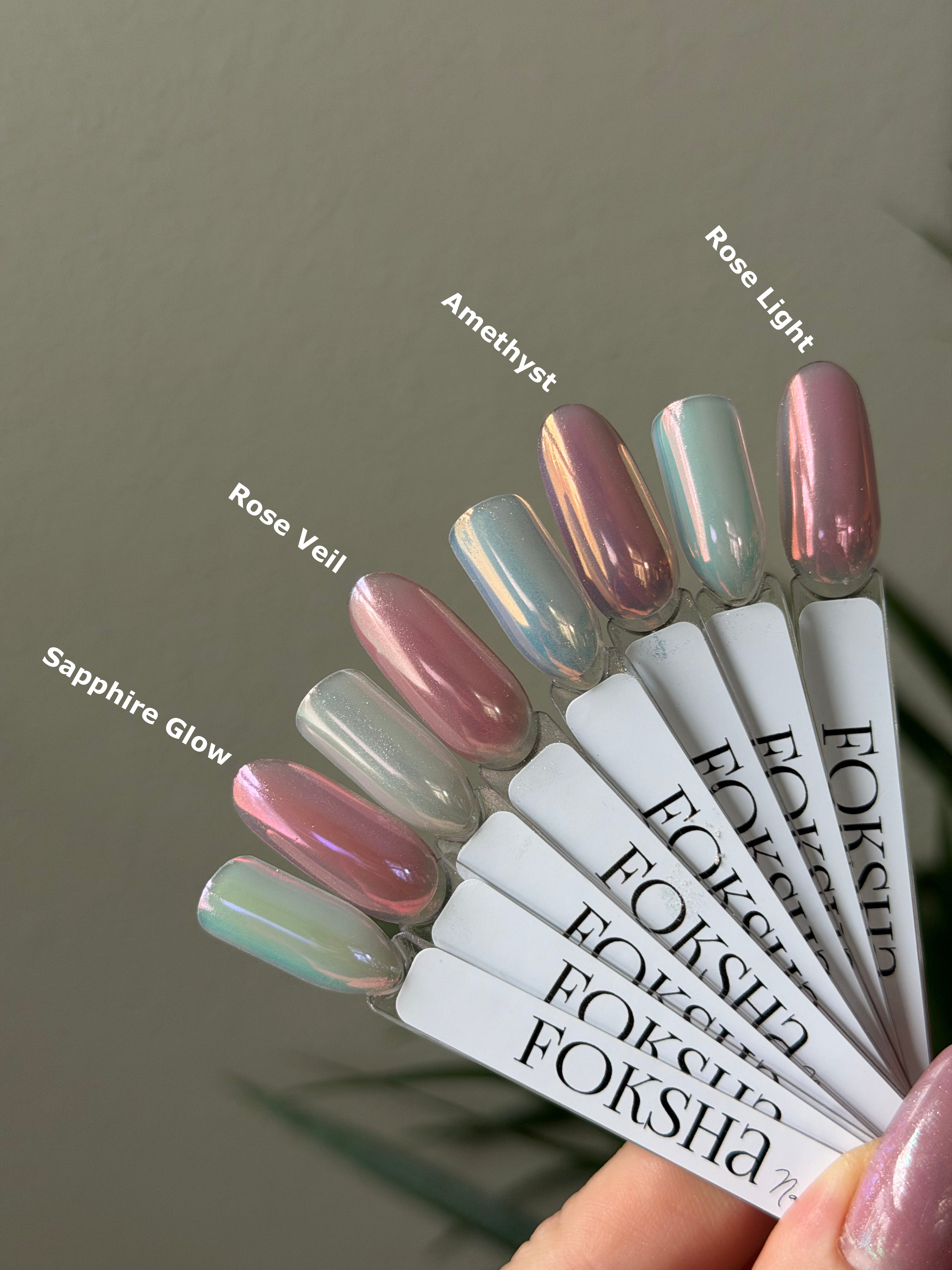 Foksha nail polish tubes with corresponding nail colors on a neutral background