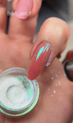 Close-up of a hand with a glittery nail design and a container of glitter.