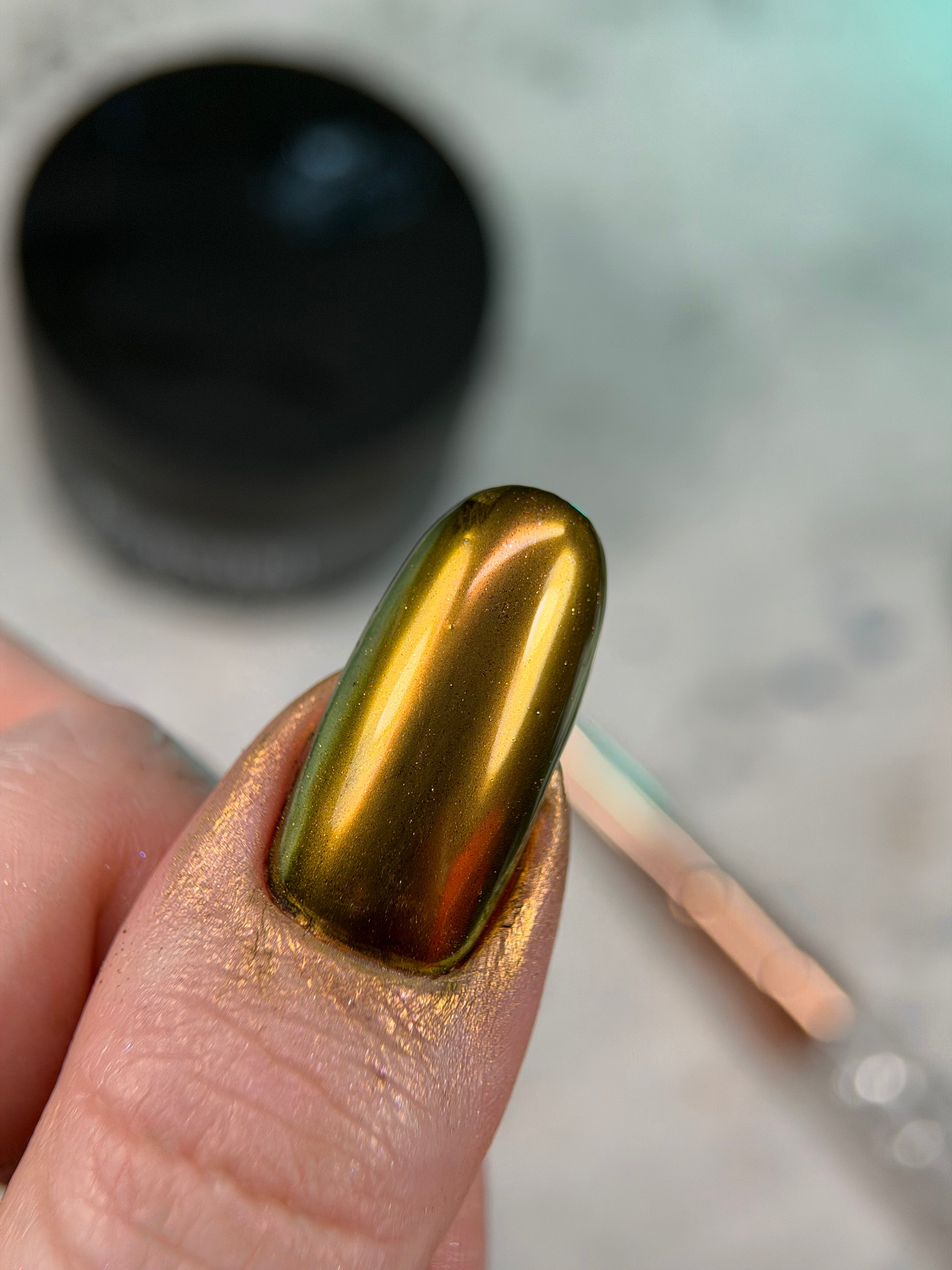 Gold nail polish on a finger with a blurred background