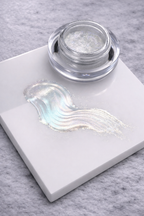 Jar of silver/blue powder on a white marble slab with a gray background