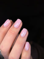 Close-up of a hand with pink and clear powder nail polish on a dark background
