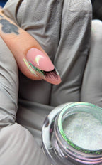 Close-up of a hand with a decorative nail design and a container of glittery nail powder.