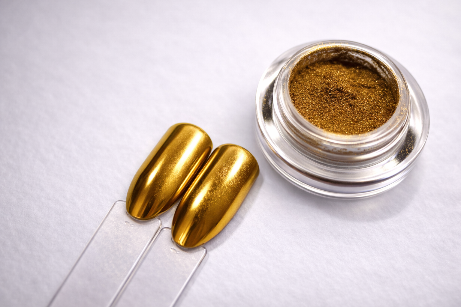 Gold-colored nail polish with a small container of powder on a white background