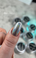 Finger with metallic nail polish in front of nail polish bottles