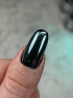 Black nail polish on a finger with a blurred background