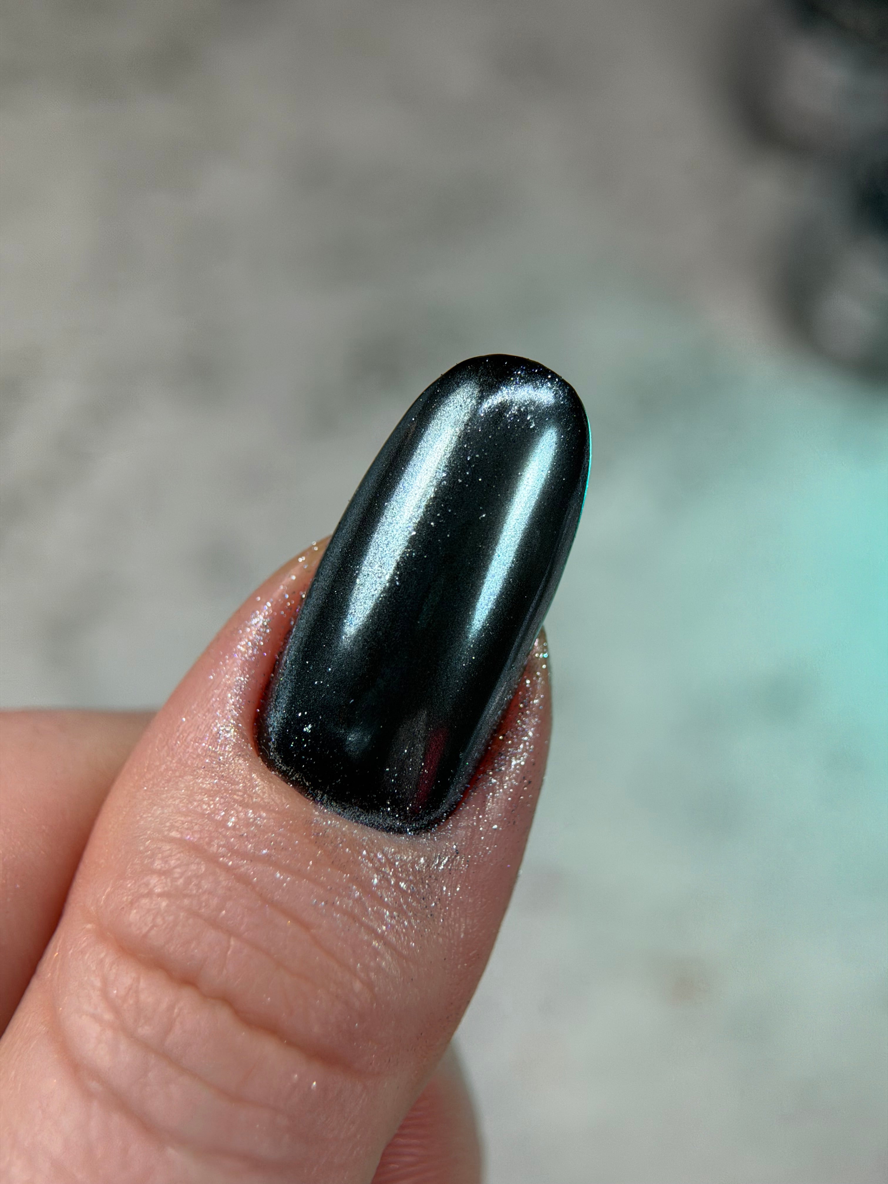 Black nail polish on a finger with a blurred background