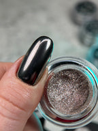 Metallic nail polish with a reflective surface on a blurred background