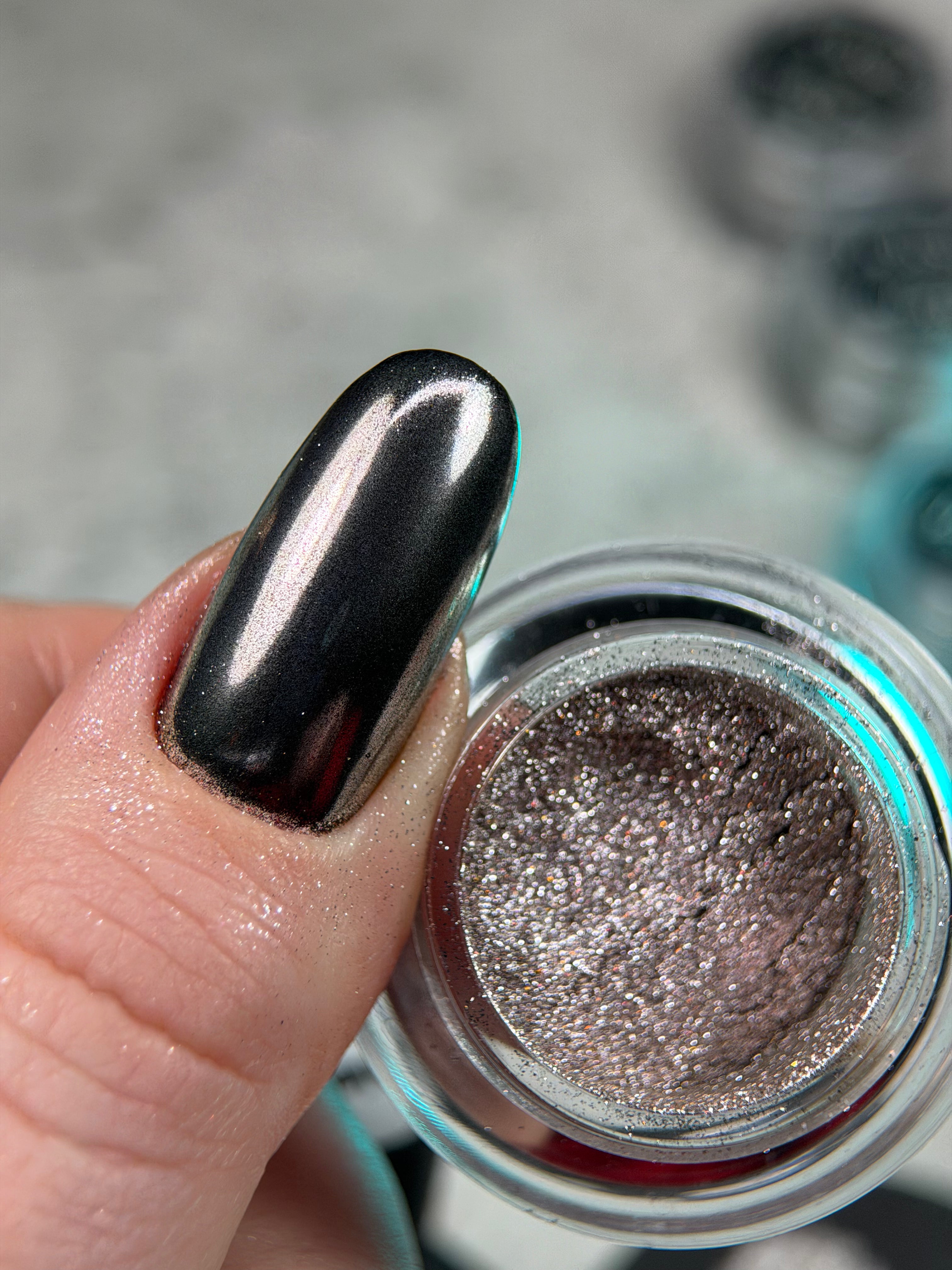 Metallic nail polish with a reflective surface on a blurred background