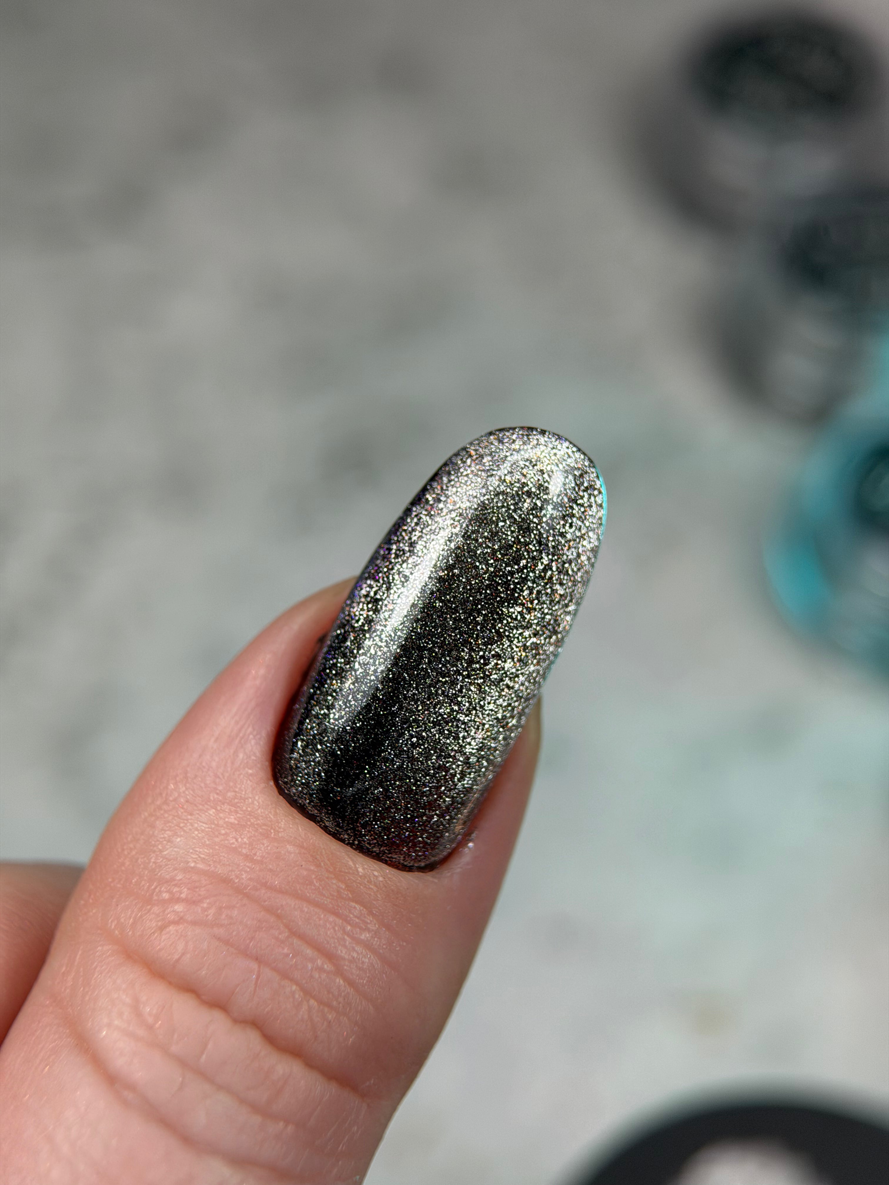 Nail with glittery black and silver polish on a blurred background