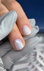 Close-up of a hand with light purple nail polish on a blurred background
