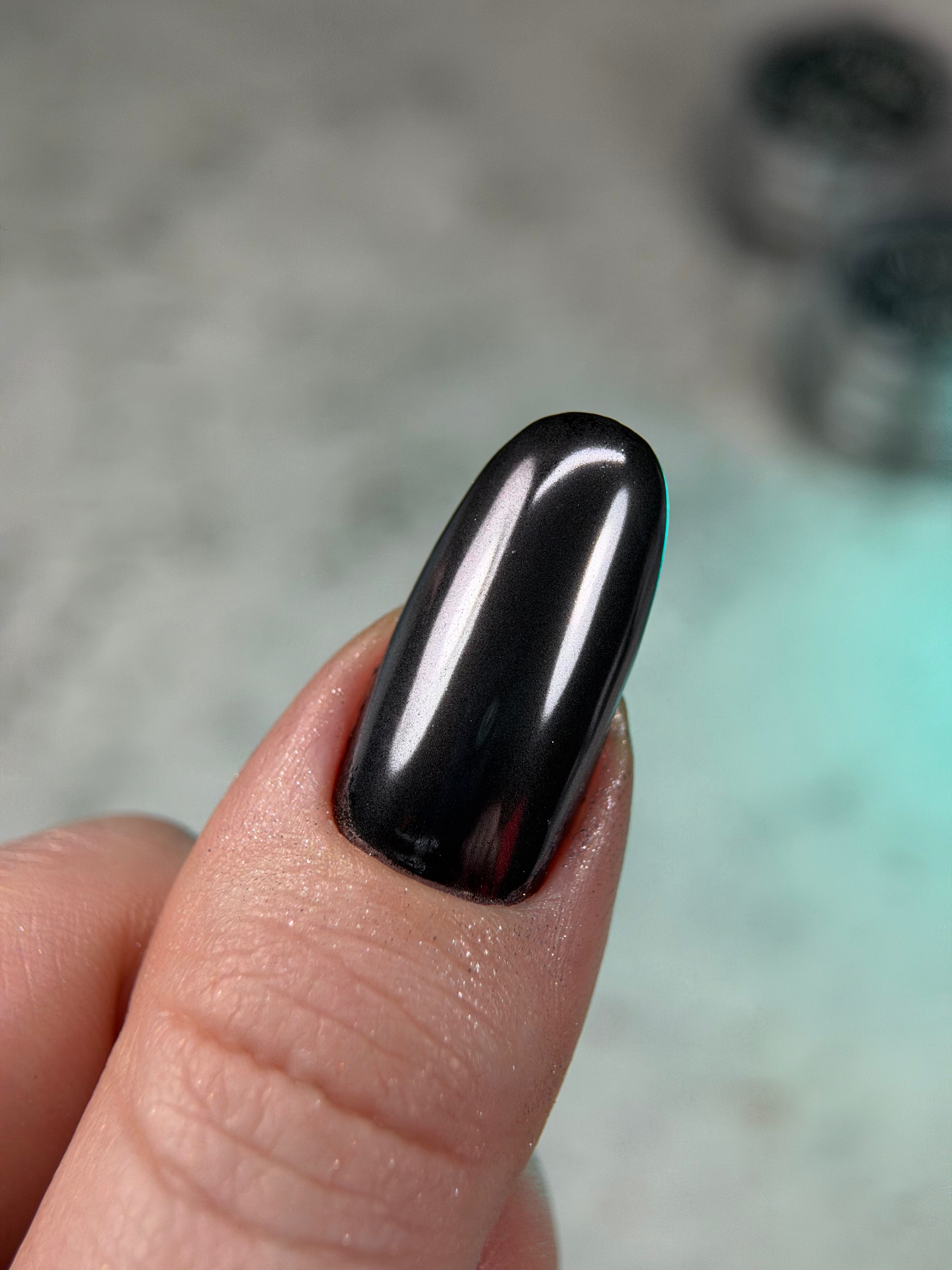 Black nail polish on a finger with a blurred background