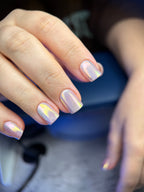 Close-up of a hand with iridescent nail polish on a blurred background