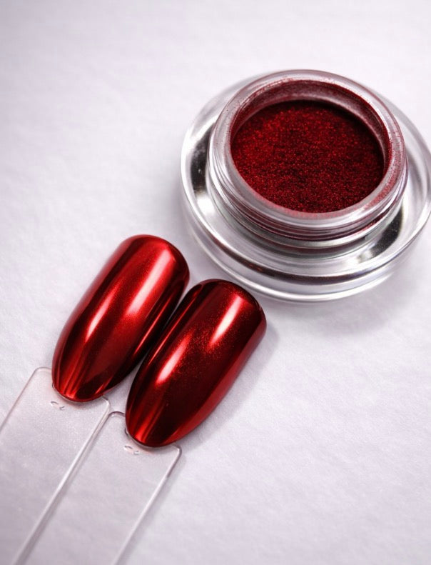 Metallic red nail polish in a jar with two red nails on a white background