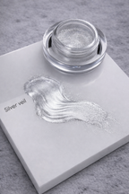 Jar of silver powder with a sample on a gray surface
