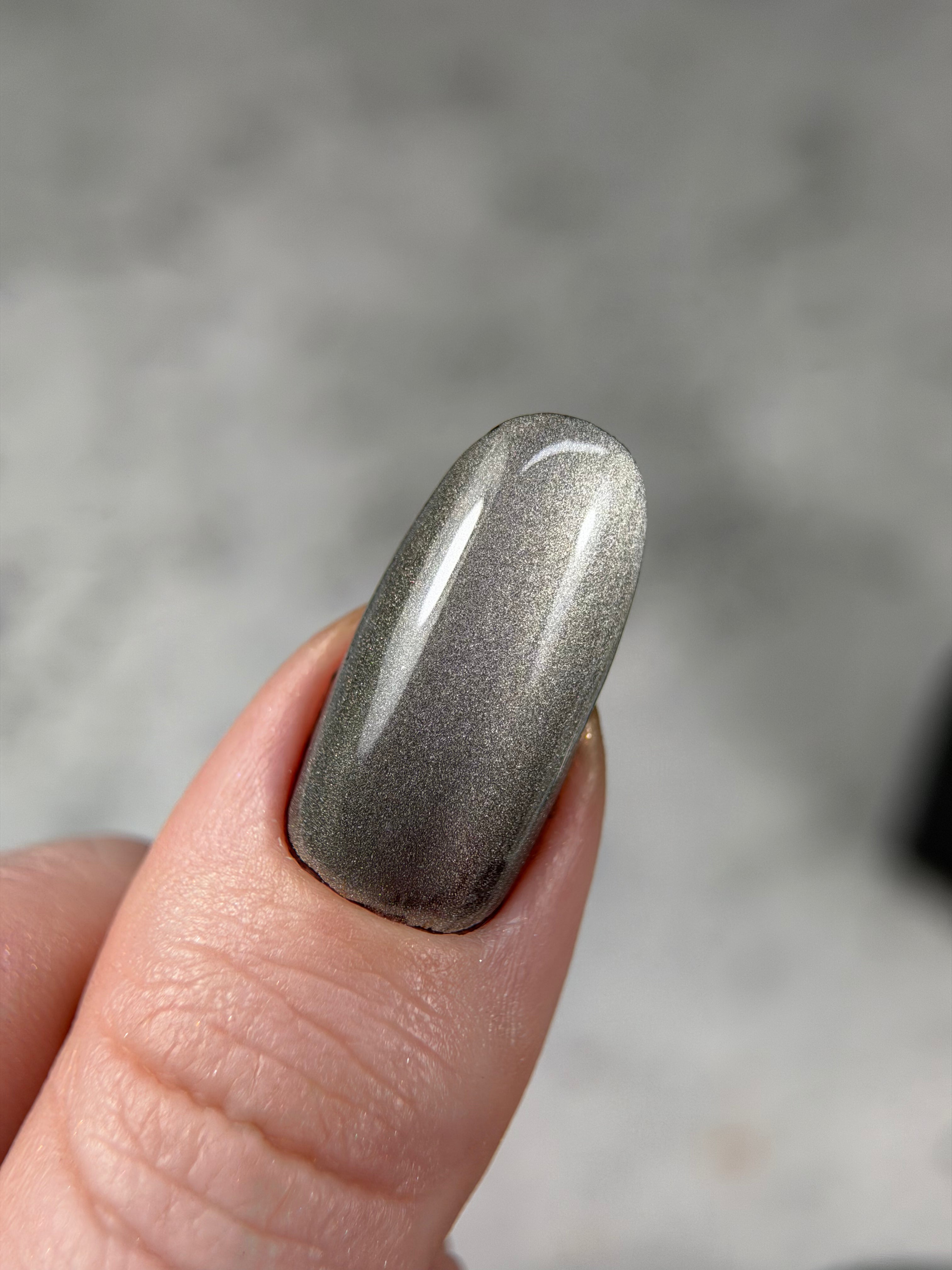 Silver metallic nail polish on a finger with a blurred background