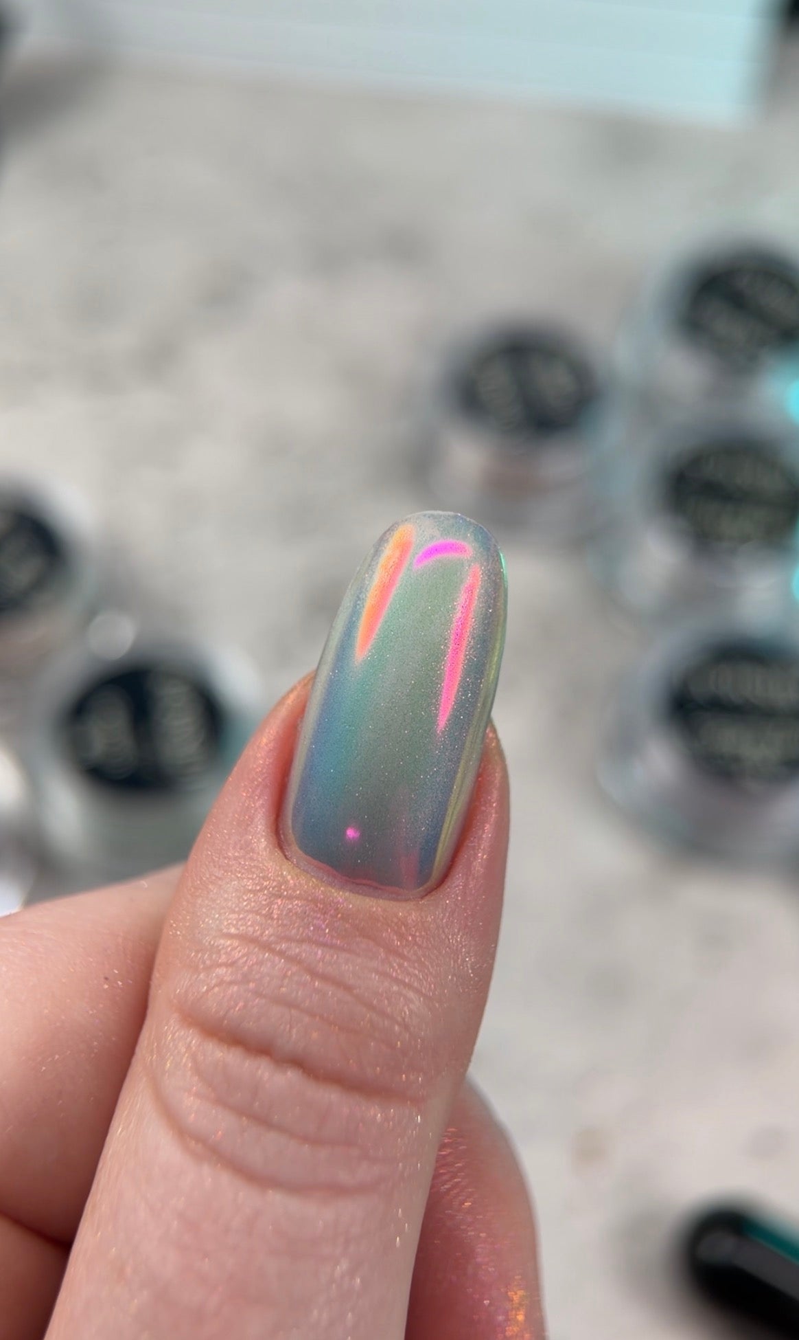 Nail with colorful design held by a hand, blurred background