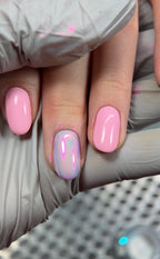 Close-up of a hand with pink and purple nail polish, wearing a gray glove.