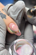 Close-up of a hand with glittery nail polish being applied, with a focus on the nail and brush.