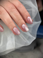 Hand with pink glittery nail polish against a white sheer fabric background