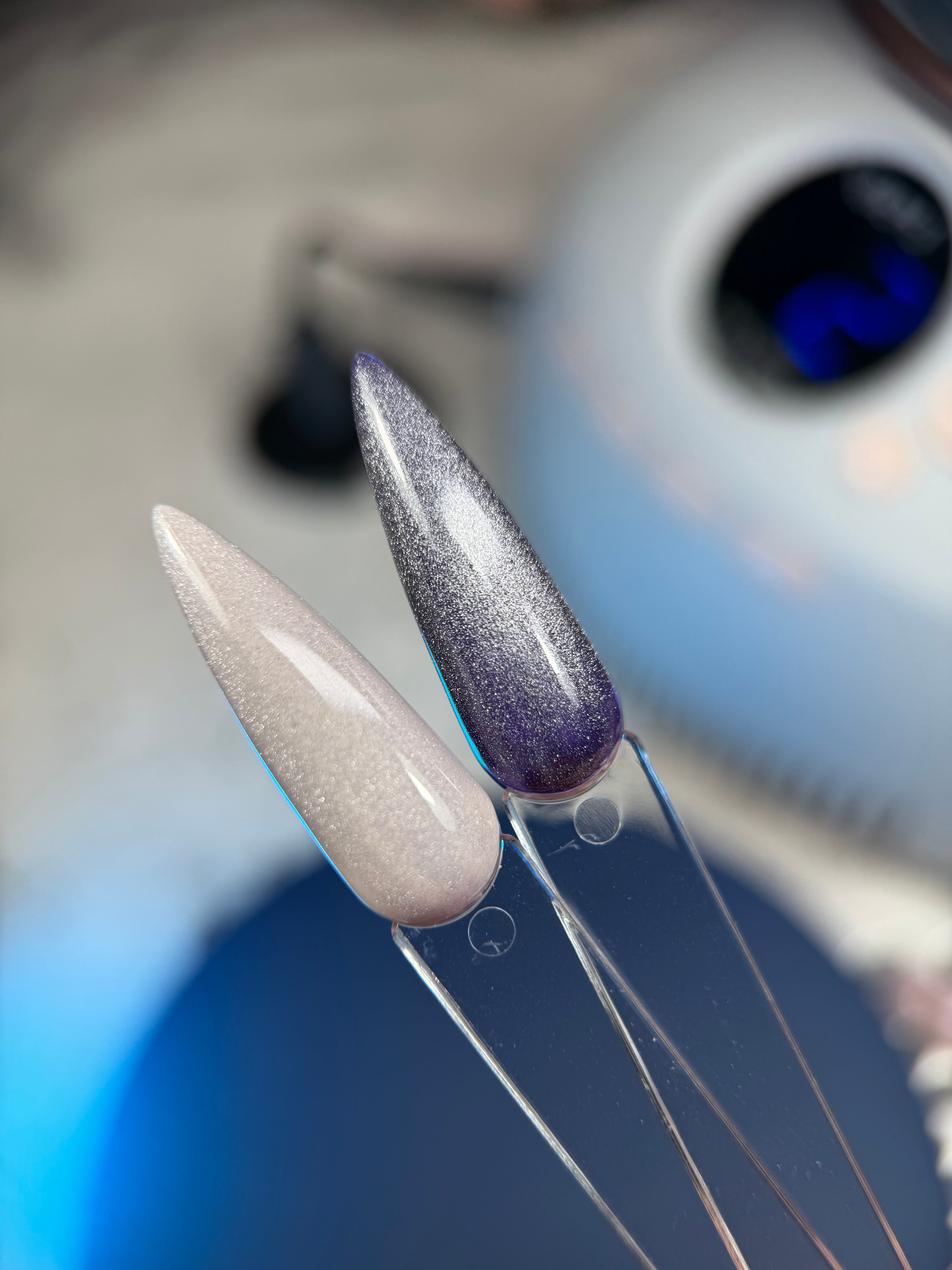 Close-up of two artificial nails with glittery finish on a blurred background