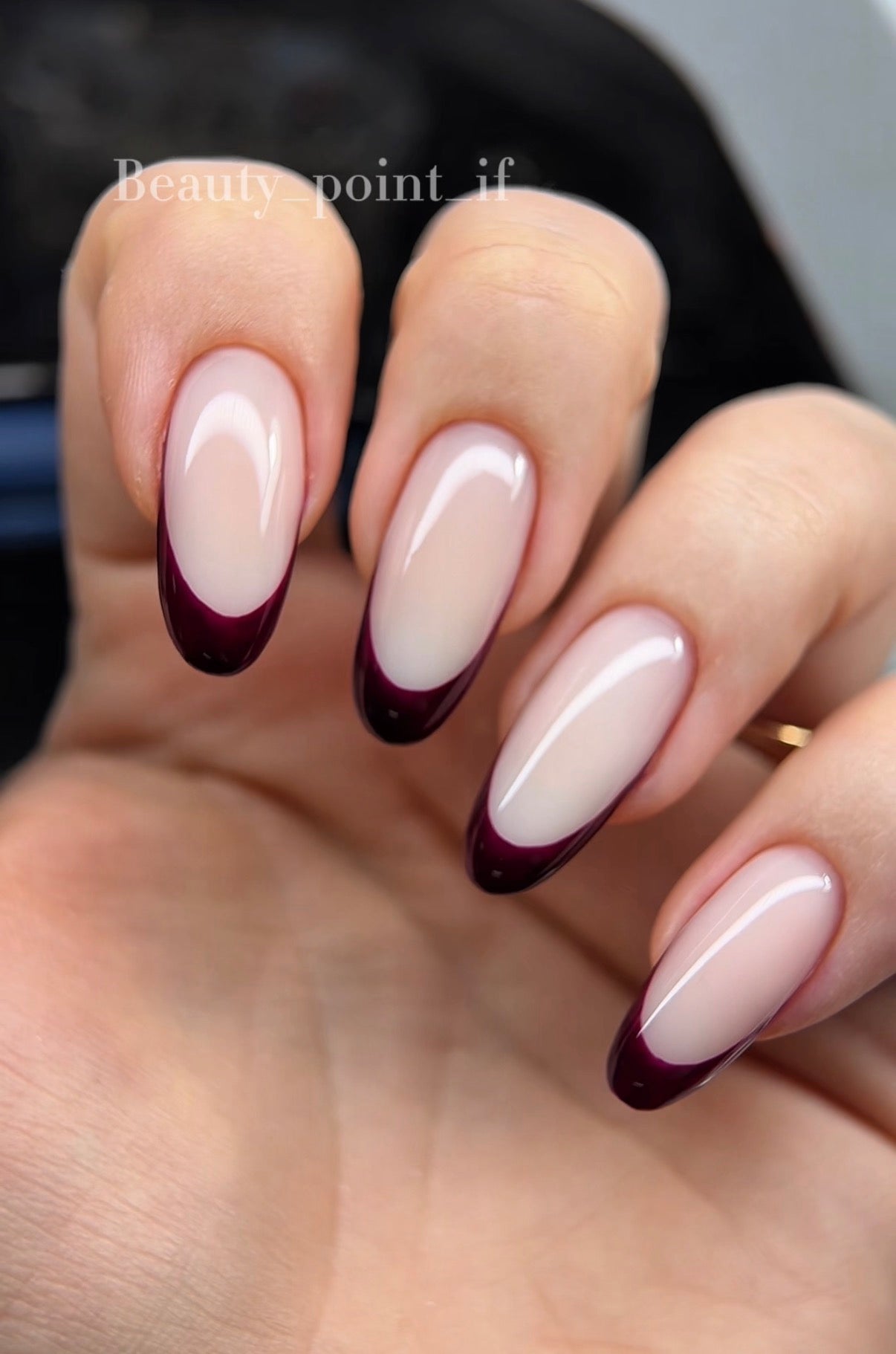 Nails with a gradient design transitioning from white to dark red on a blurred background.